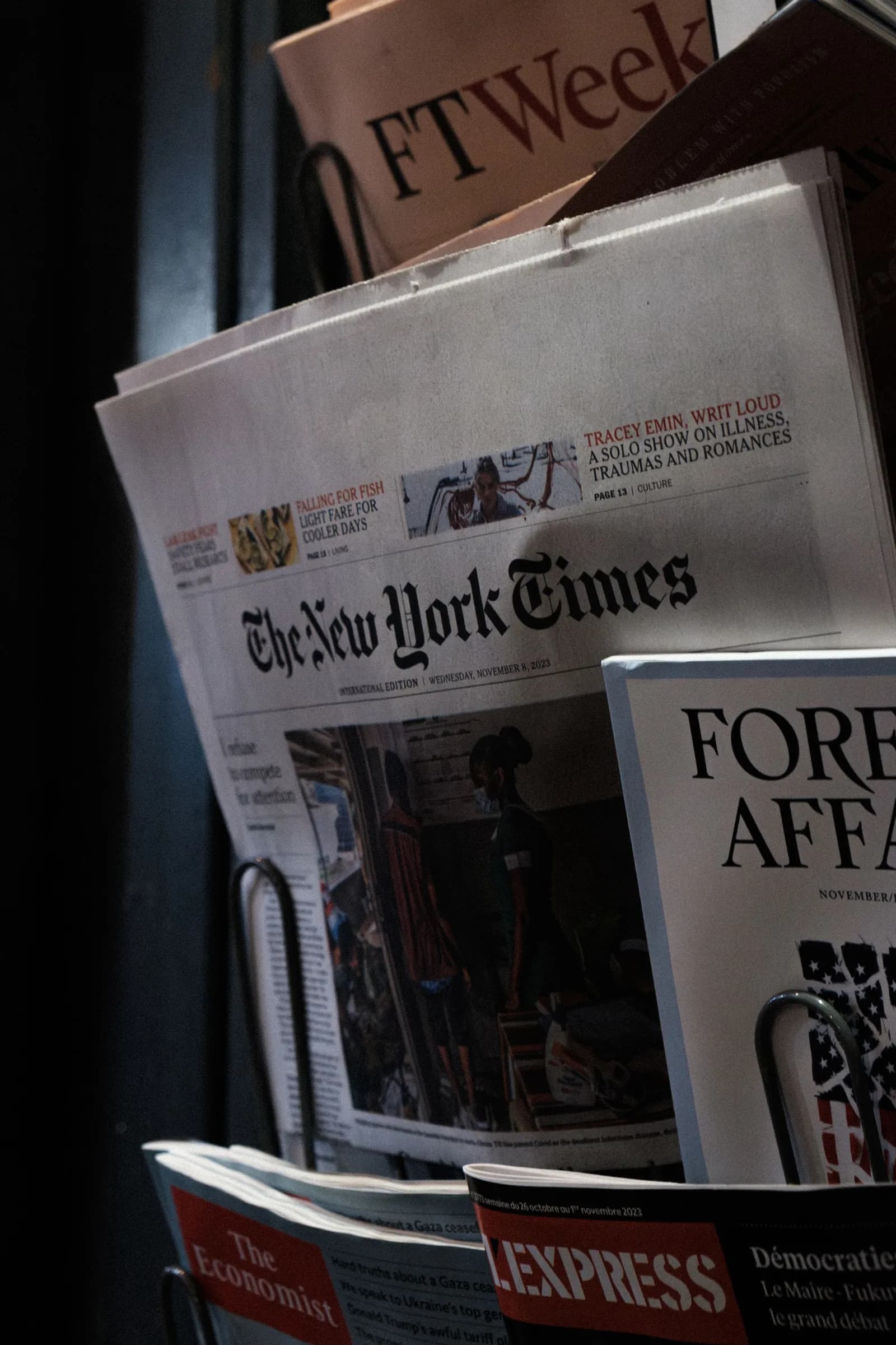 Newspapers and magazines stacked at a newsstand
